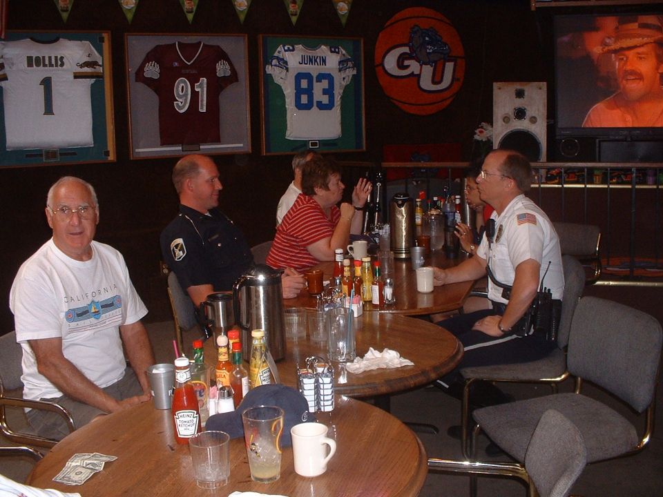 People sitting at tables in a bar with sports memorabilia on the wall