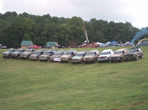 1994 Ford Bronco - A group of Ford Broncos and F-150s are parked in a line on a grassy field during an event.