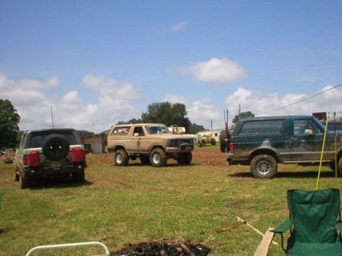 1994 Ford Bronco - Three Ford Broncos are parked in a field on a sunny day.