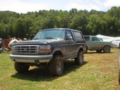 1994 Ford Bronco - A dark-colored Ford Bronco, appearing to be from the early to mid-1990s, is parked outdoors with another vehicle in the background.