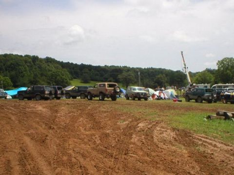 1994 Ford Bronco - Several SUVs are parked in a grassy field with tents and trees in the background.