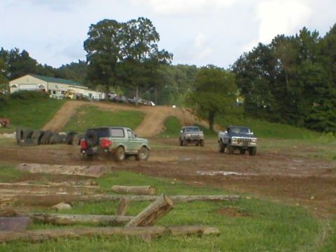 1994 Ford Bronco - Several off-road vehicles navigate a challenging course with muddy tracks and obstacles.