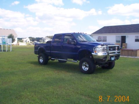 1978 Ford Bronco - This lifted blue Ford F-250 Super Duty pickup truck is parked on a grassy lawn in front of a house.