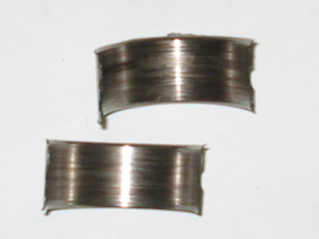 Two curved metal engine bearing shells on light background