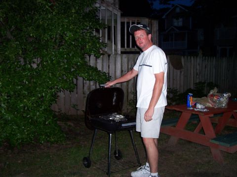 1994 Ford Bronco - A man stands by a charcoal grill in a backyard setting as evening approaches.