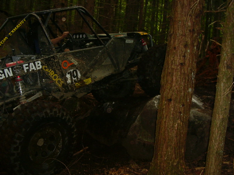 Off-road buggy with roll cage navigating rocks in a forest