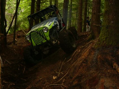 1990 Ford Bronco - An off-road vehicle navigates a steep, wooded trail.