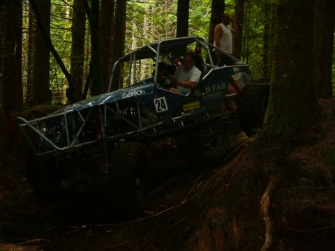 1990 Ford Bronco - A custom-built off-road buggy, identified by the number 24, navigates a challenging wooded terrain.