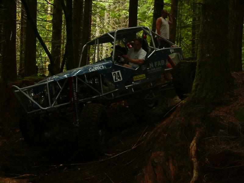 Custom off-road buggy with number 24 on side, navigating a wooded trail
