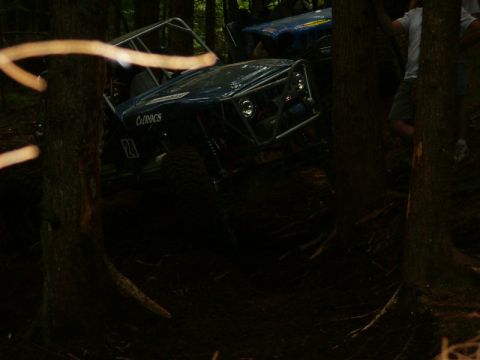 1990 Ford Bronco - Two off-road vehicles are seen navigating a wooded area.