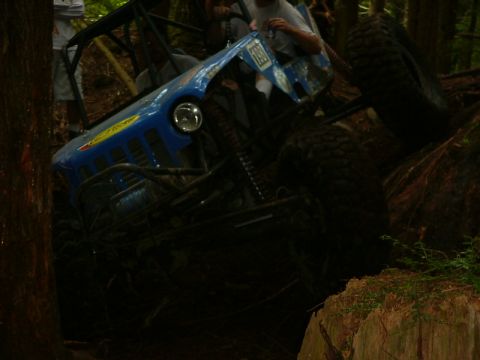 1990 Ford Bronco - An off-road vehicle navigates a challenging wooded terrain.