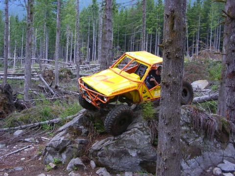 1990 Ford Bronco - This off-road vehicle navigates a rocky trail in a dense forest environment.