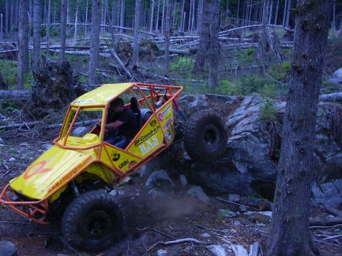 1990 Ford Bronco - A custom-built off-road buggy navigates a rocky trail in a wooded area.