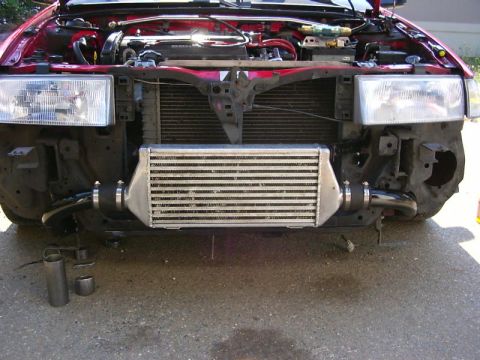 1990 Ford Bronco - The front of a red car is shown with its hood open, revealing the engine and an installed intercooler.