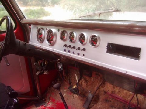 1978 Ford Bronco - Interior shot of a stripped early Bronco showing a custom white-painted dash panel with a row of six chrome-bezel aftermarket gauges and fo…