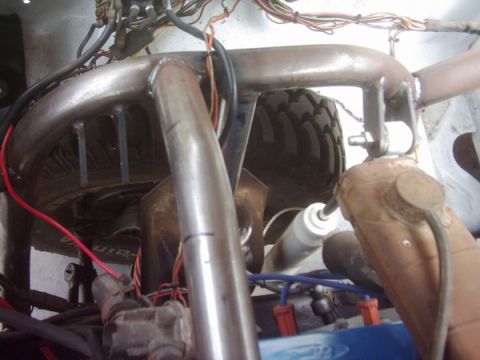 1978 Ford Bronco - Close-up view of custom roll cage tubing and engine bay components, including a tire and shock absorber.