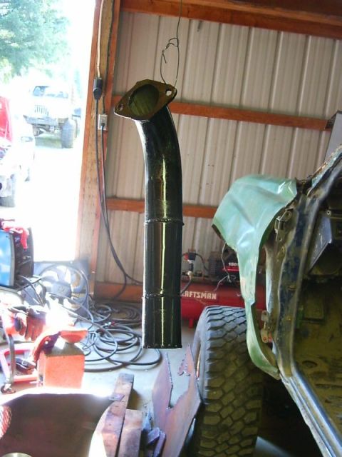 1990 Ford Bronco - A freshly painted exhaust pipe hangs in a garage, awaiting installation on a vehicle.