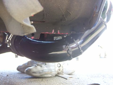 1990 Ford Bronco - Underside view of a vehicle's exhaust system, with a person's shoes visible beneath.