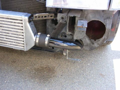 1990 Ford Bronco - Close-up view of aftermarket intercooler and piping installed on a vehicle's front end.
