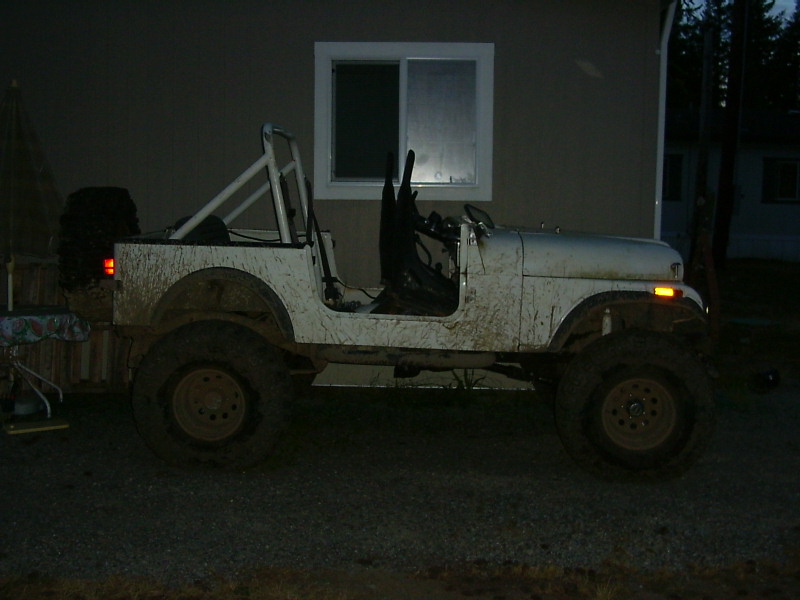 White Jeep CJ side view, covered in mud, with a roll cage