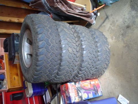 1993 Ford Bronco - A stack of four tires sits on top of some boxes in a cluttered garage.