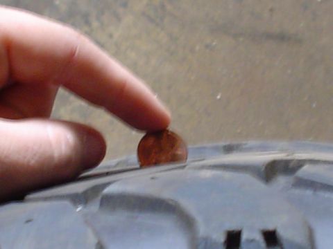 1993 Ford Bronco - A penny is used to check the tread depth on a tire.