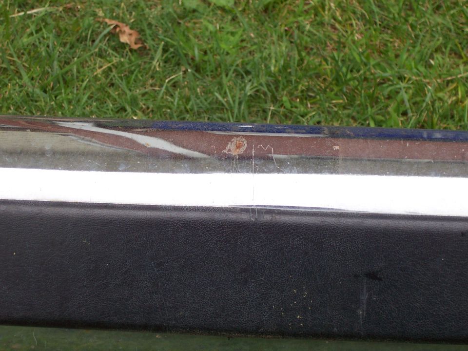close-up of chrome bumper with rust spot and black trim