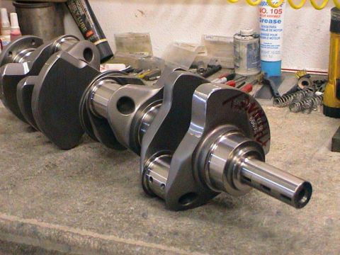 1979 Ford Bronco - A close-up view of a metal crankshaft, likely for an engine, resting on a concrete surface.
