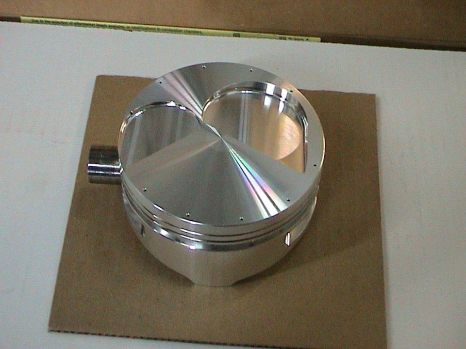 New forged aluminum domed piston with valve reliefs standing on cardboard