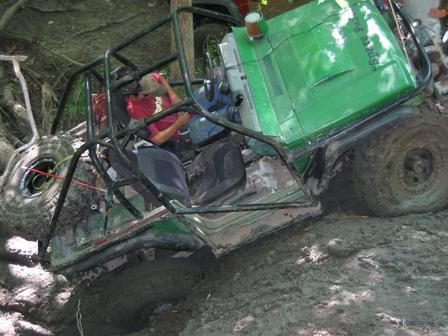 1992 Ford Bronco - Off-road vehicle with roll cage stuck deep in mud.