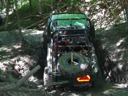1992 Ford Bronco - This vehicle is navigating a difficult, muddy path surrounded by trees.
