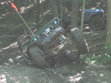 1992 Ford Bronco - An off-road vehicle is stuck in the mud, with another vehicle visible behind it in the woods.