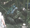 1992 Ford Bronco - An overturned vehicle lies amidst dense foliage, its wheels pointing skyward.