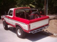 1978 Ford Bronco - Rear view of a two-tone red and white 1978 Ford Bronco with a custom roll cage and spare tire.