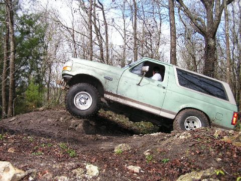 1994 Ford Bronco - A 1994 Ford Bronco navigates a challenging off-road terrain with one wheel lifted.