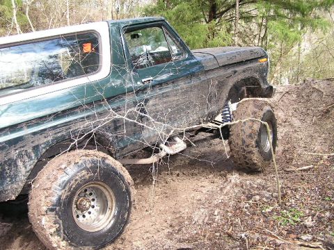 1994 Ford Bronco - This heavily muddied 1978 Ford Bronco navigates a challenging off-road terrain.
