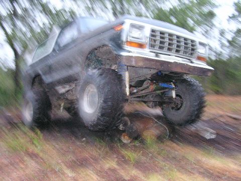 1994 Ford Bronco - This modified Ford Bronco is navigating a challenging off-road terrain with large tires and lifted suspension.