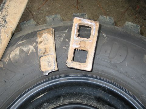 1995 Ford Bronco - Two metal brackets are placed on a tire. The tire has a large 'D' logo on its sidewall.