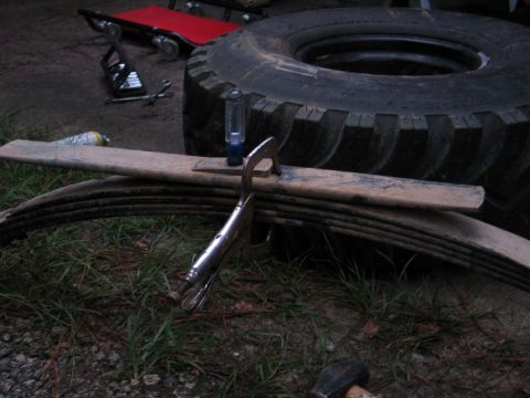 1995 Ford Bronco - Leaf springs and a large tire are visible, along with tools, suggesting vehicle maintenance.
