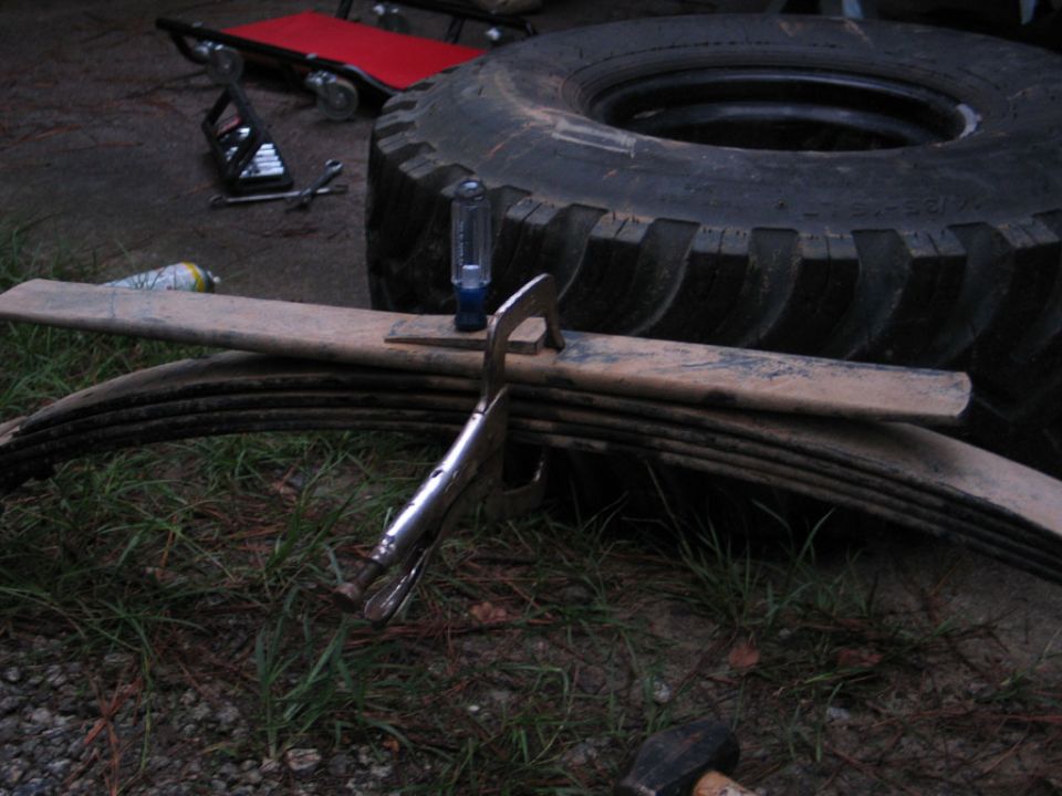 Leaf springs clamped together with vice grips, next to a large tire