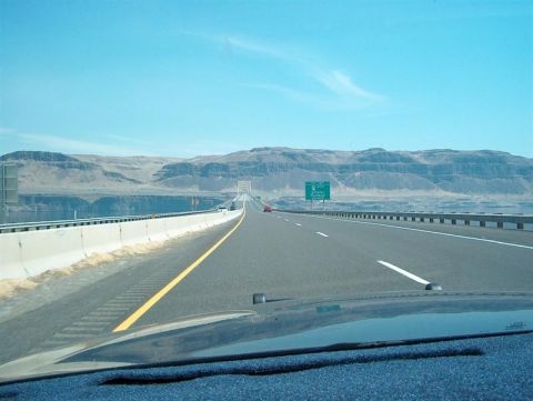 2001 Ford Crown Victoria - Driving on a highway with a concrete barrier and distant mountains under a clear blue sky.