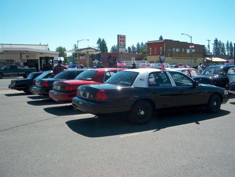 2001 Ford Crown Victoria - Several police cars, including a 2001 Ford Crown Victoria, are parked in a lot on a sunny day.