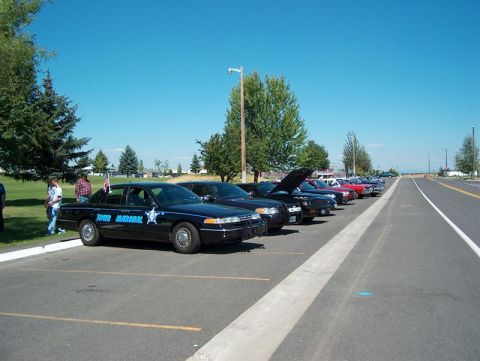2001 Ford Crown Victoria - Several police cars, including a Ford Crown Victoria, are parked in a lot on a sunny day.