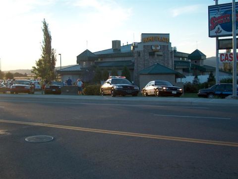 2001 Ford Crown Victoria - Several vehicles, including a police car, are parked in front of the Home Plate building.
