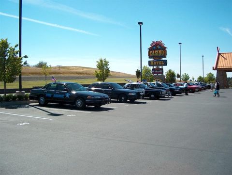 2001 Ford Crown Victoria - A fleet of police vehicles, including a 2001 Ford Crown Victoria, are parked outside a casino and hotel.