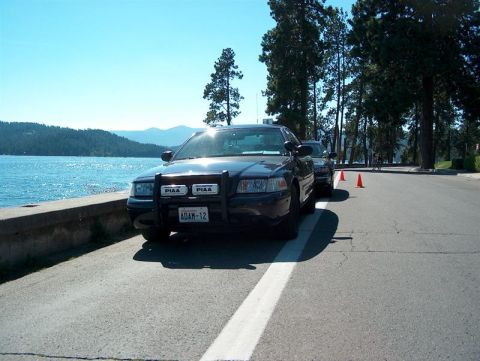 2001 Ford Crown Victoria - A police car is parked next to a body of water with trees in the background.