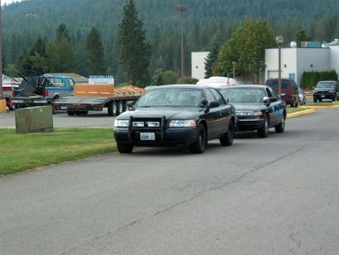 2001 Ford Crown Victoria - A line of police interceptors are parked in a lot, with a trailer and truck in the background.