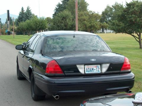 2001 Ford Crown Victoria - Rear view of a black 2001 Ford Crown Victoria with a Washington license plate reading 'ADAM-12'.