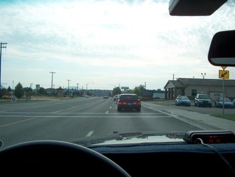 2001 Ford Crown Victoria - Driving through town on a cloudy day, passing other vehicles and businesses.