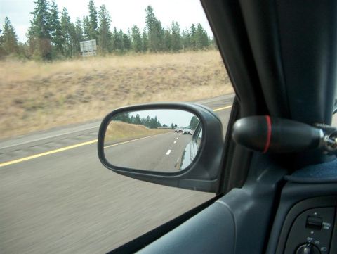 2001 Ford Crown Victoria - View from inside a car traveling on a highway, showing the road ahead and other vehicles in the side mirror.